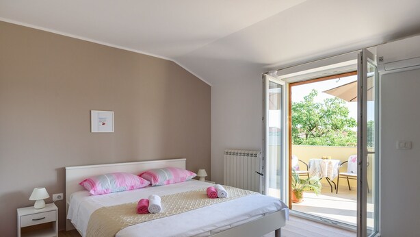 Een slaapkamer met een bed, nachtkastje en uitzicht op een terras.