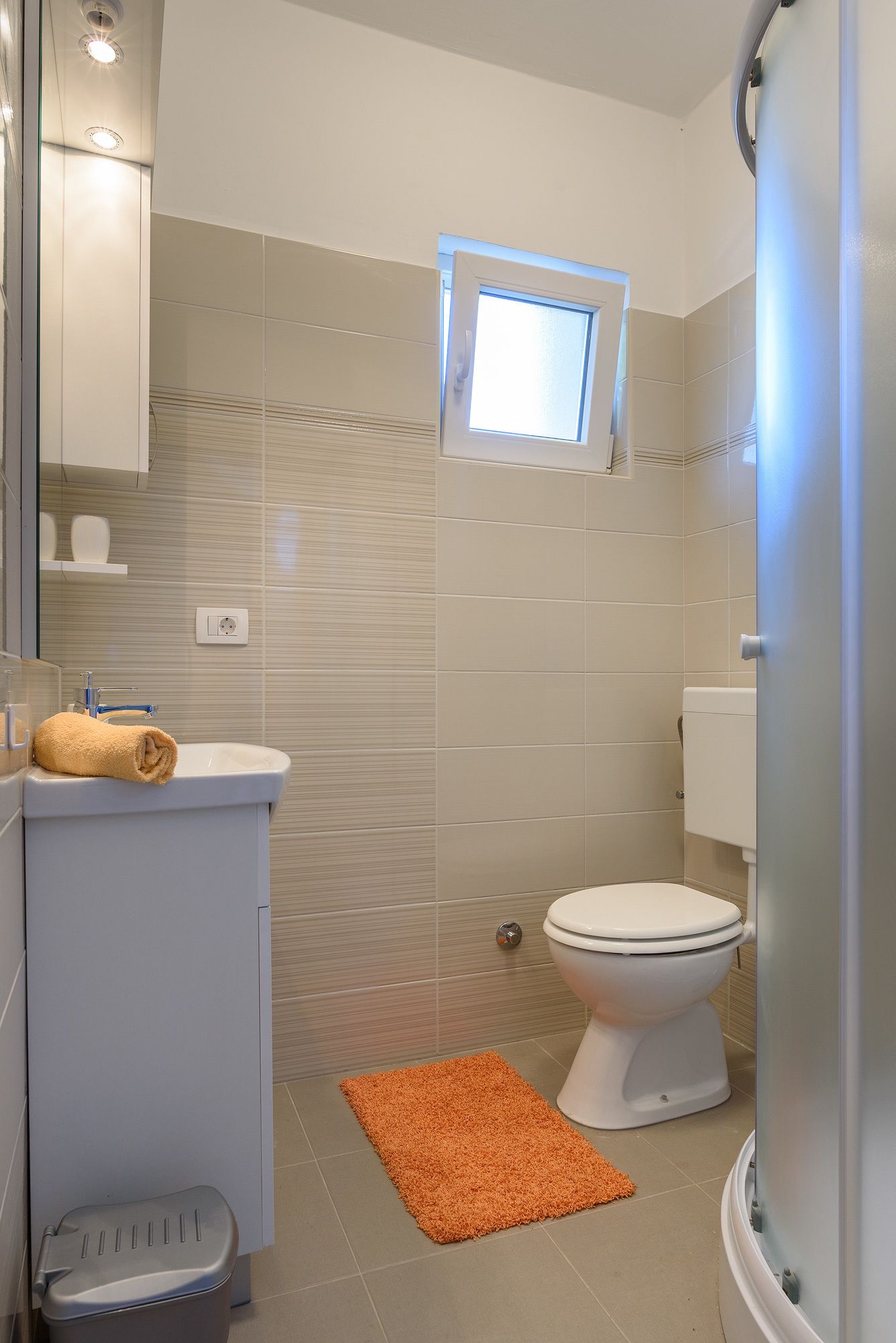 A bathroom with a toilet, sink, and a small window.