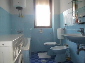 Une salle de bain équipée d’un lave-linge, de deux toilettes, d’un bidet et d’un lavabo.