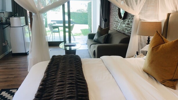 A hotel room with a bed, a sofa, a lamp, and a view of the outdoor area. - The Leslie - Bed & Breakfast (Blantyre)