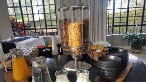 A breakfast buffet setup with a coffee station, cereal dispensers, and a fruit bowl. - The Leslie - Bed & Breakfast (Blantyre)