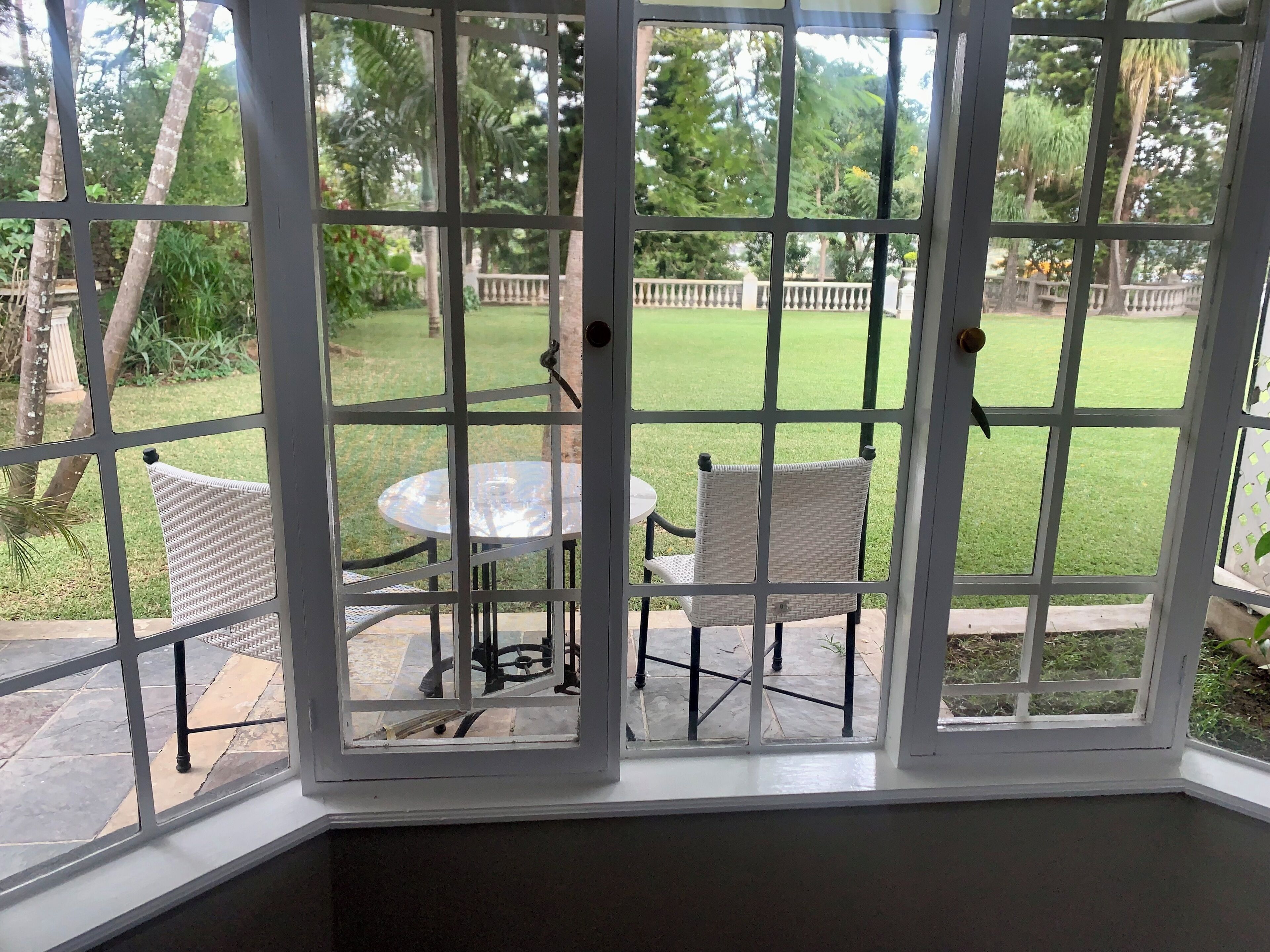 A conservatory with a glass door, a round table, and two wicker chairs.