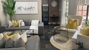 A living room with a grey sofa, a round coffee table, and a large plant. - The Leslie - Bed & Breakfast (Blantyre)