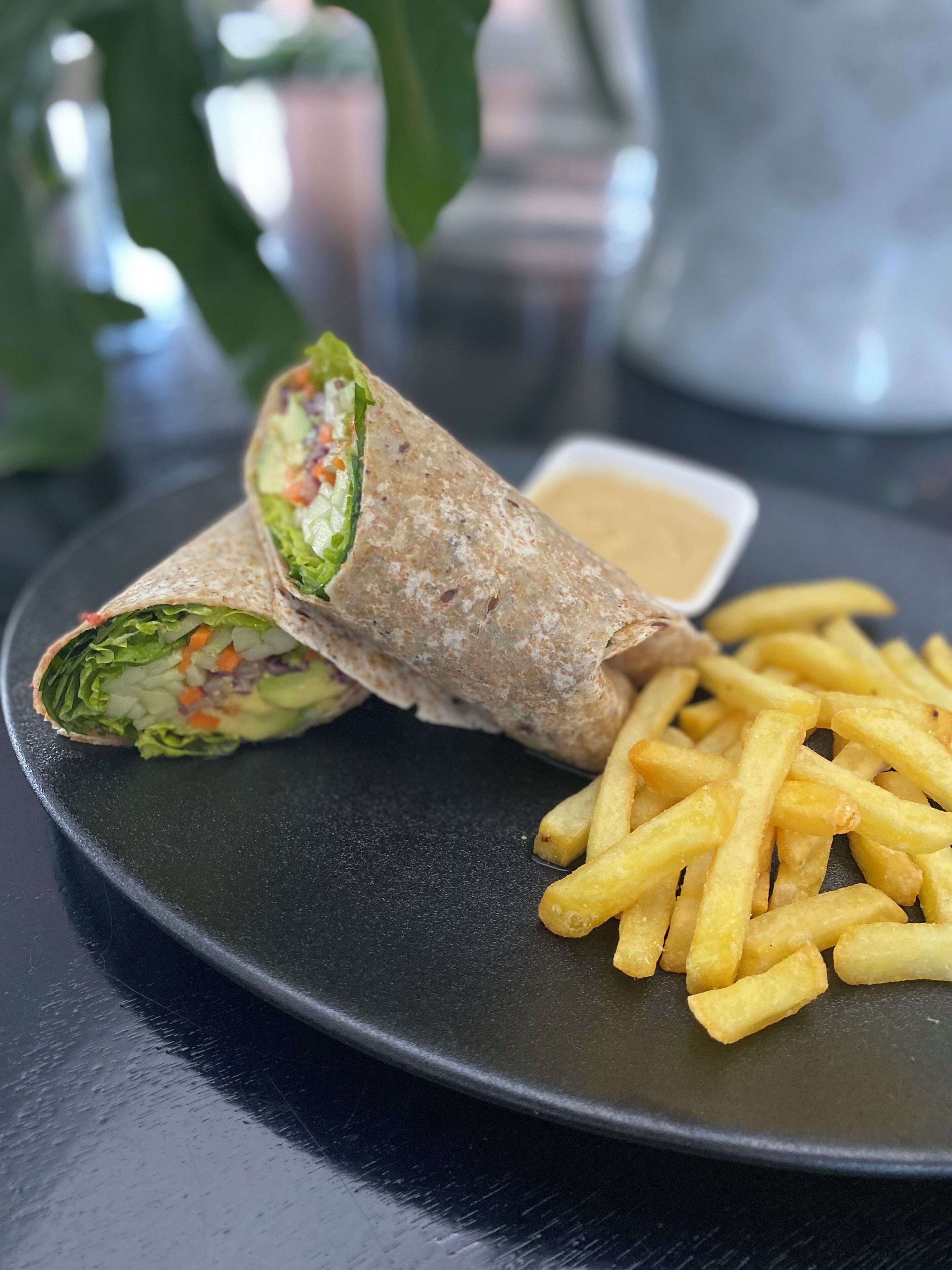 A plate with a wrap and fries.