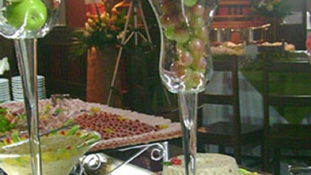 Zona de menjador amb barra de buffet, incloent pastís i diferents plats.