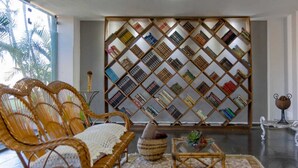 Habitació amb mobles de vimetlla, una catifes amb motius i una prestatgeria plena de llibres.