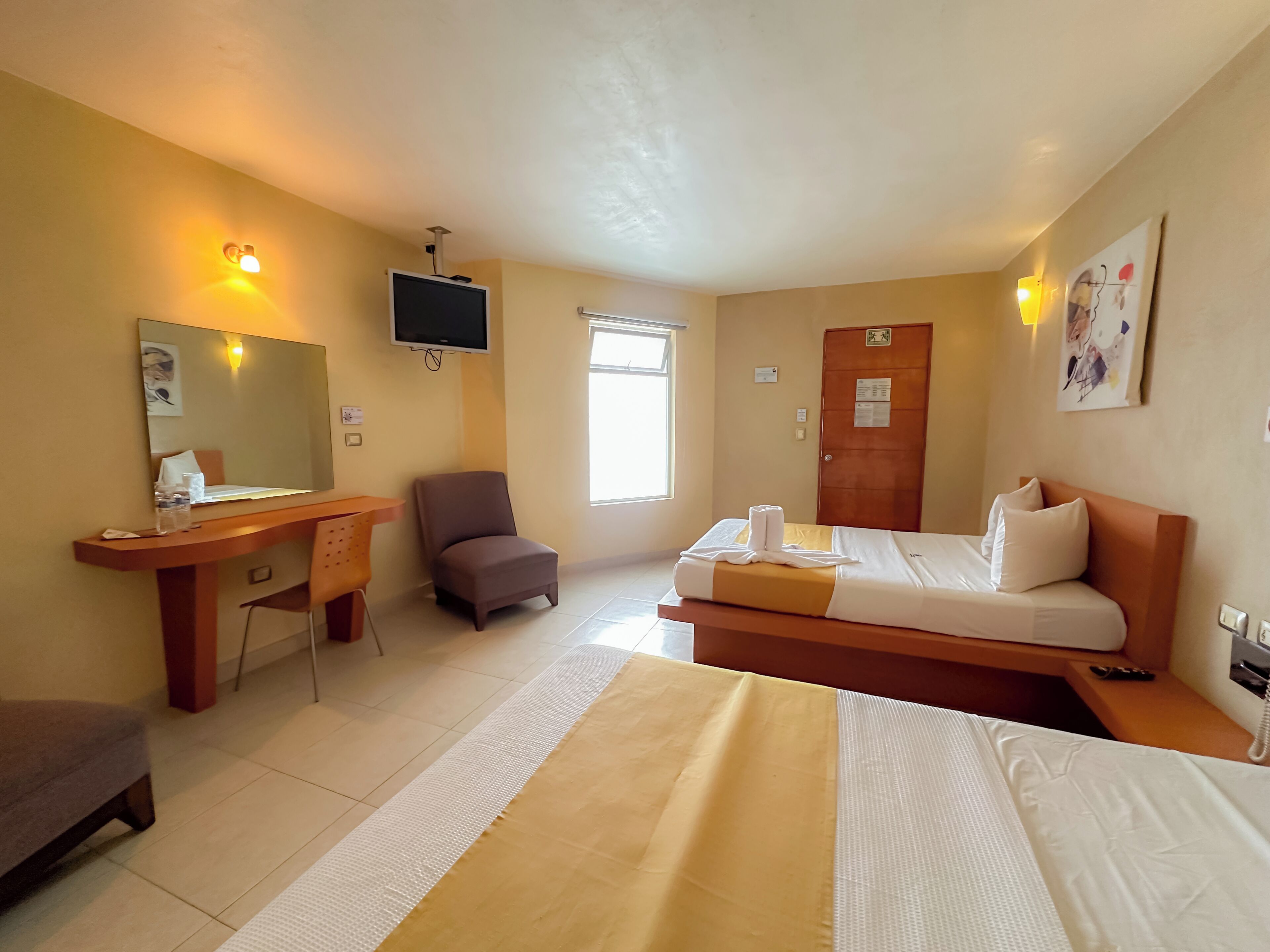 Ein Hotelzimmer mit Bett, Schreibtisch, Stuhl, Fernseher und Fenster.
