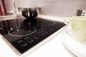 A modern induction cooktop with a digital control panel and a white mug on a white tray. - ComfortHouse Plus (Rome)
