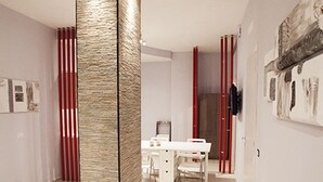 Ein modernes Interieur mit einer zentralen Säule, einem Essbereich mit weißem Tisch und Stühlen sowie Kunstwerken an den Wänden.
