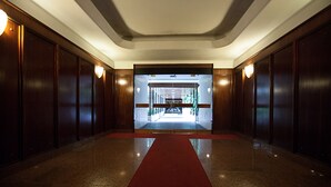 Ein Hotelkorridor mit einem roten Teppich, der zu einem Glastür-Eingang führt.