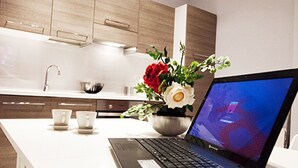 Eine moderne Küche mit Holdekor-Schränken, einer weißen Arbeitsplatte und einem Laptop, der einen blauen Bildschirm anzeigt.