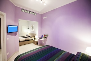 A bedroom with a bed, a desk, a chair, a TV, and a mirror. - ComfortHouse Plus (Rome)