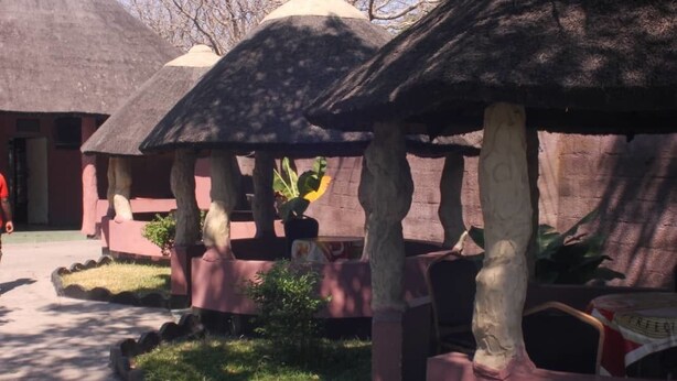 A traditional hut structure with a thatched roof, surrounded by a low wall and a small garden area. - Nalumba 2 Lodge (Mongu)