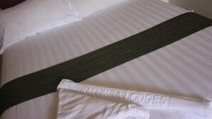A neatly made bed with white linens and a dark green bedspread. - Nalumba 2 Lodge (Mongu)