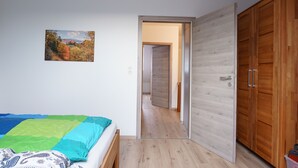 A bedroom with a bed, a wooden wardrobe, and a hallway leading to another room. - FeWo Walter - House 2 St.- Andreasberg, south-facing slope, quiet, family-friendly, WLAN (St. Andreasberg)