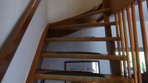 A wooden staircase with a handrail, leading to a landing with a light fixture and framed pictures on the wall. - FeWo Walter - House 2 St.- Andreasberg, south-facing slope, quiet, family-friendly, WLAN (St. Andreasberg)