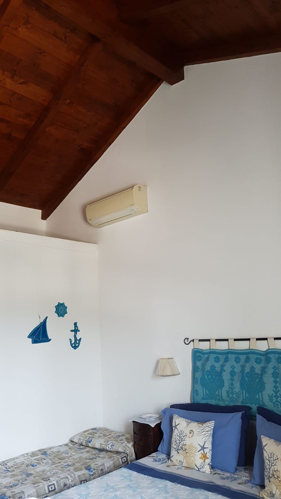 Una camera da letto con un letto, un comodino, una lampada a parete e un ventilatore a soffitto.