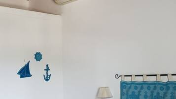 Una camera da letto con un letto, un comodino, una lampada a parete e un ventilatore a soffitto.