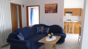 Un sofá azul con una pequeña mesa de madera en una sala de estar con vista a una cocina.