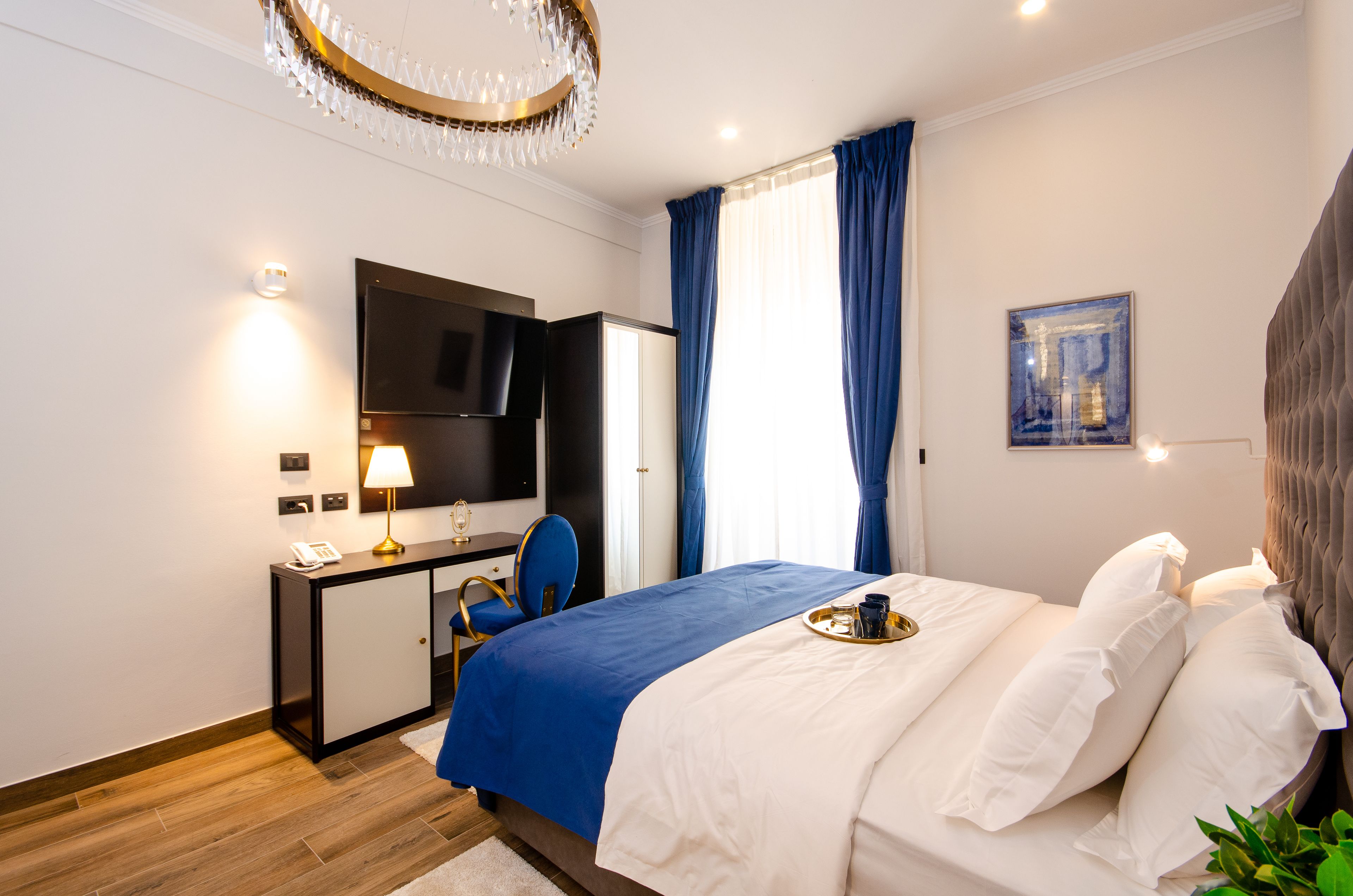 Una camera d'albergo moderna con un letto, una scrivania, una sedia, una televisione e una finestra con tende.