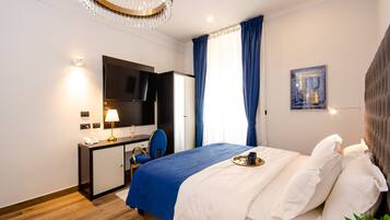 Une chambre d’hôtel moderne équipée d’un lit, d’un bureau, d’une chaise, d’une télévision et d’une fenêtre avec des rideaux.
