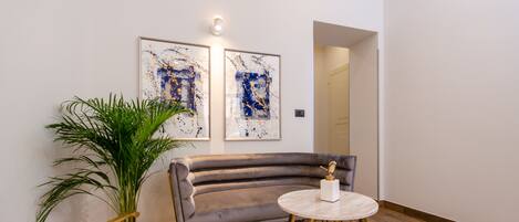 A modern living room with a grey sofa, a round coffee table, and a potted plant.