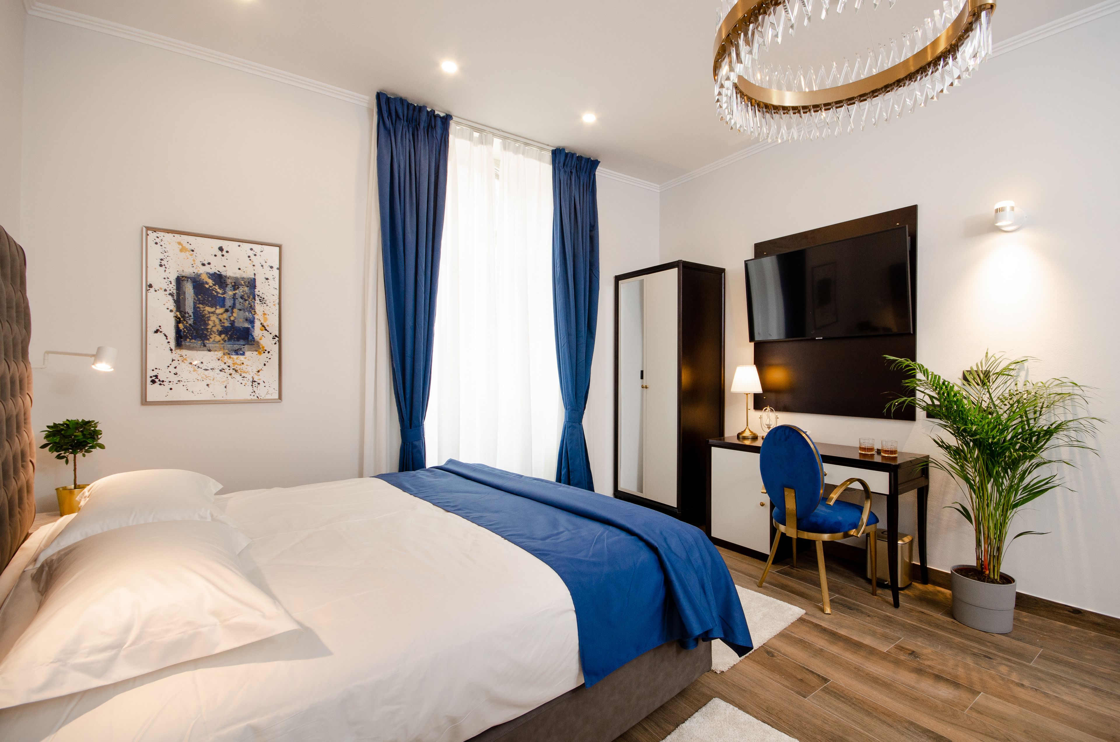 Un dormitorio moderno con cama, escritorio, silla, televisor y candelabro.