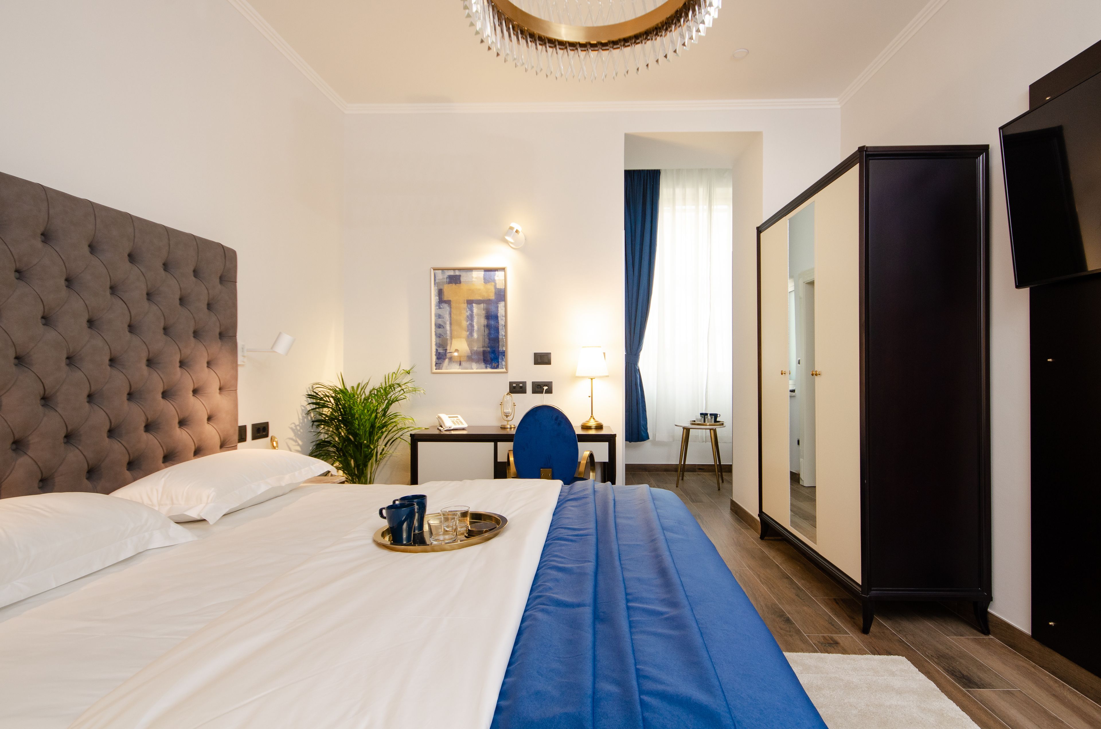 Una habitación de hotel con una cama grande, un escritorio, una silla, un armario y un espejo.