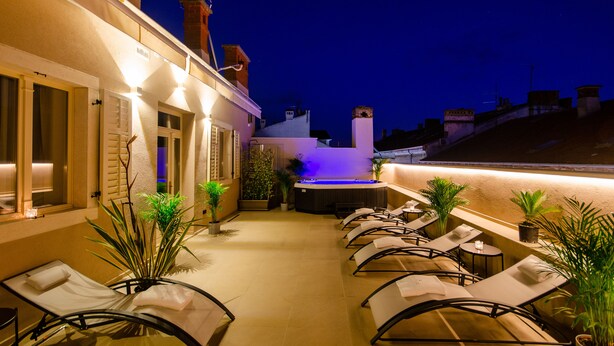 Terraza en la azotea con sillones, una bañera de hidromasaje y plantas en macetas.