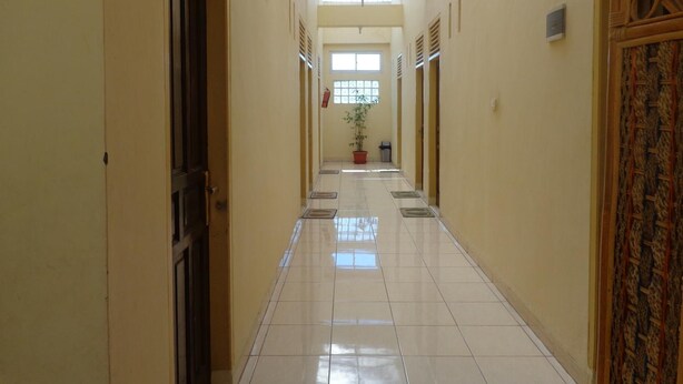 A long, narrow hallway with tiled floors and a skylight. - Hotel Musafir Inn (Padang)