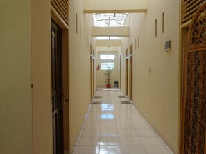 A long, narrow hallway with tiled floors and a skylight. - Hotel Musafir Inn (Padang)