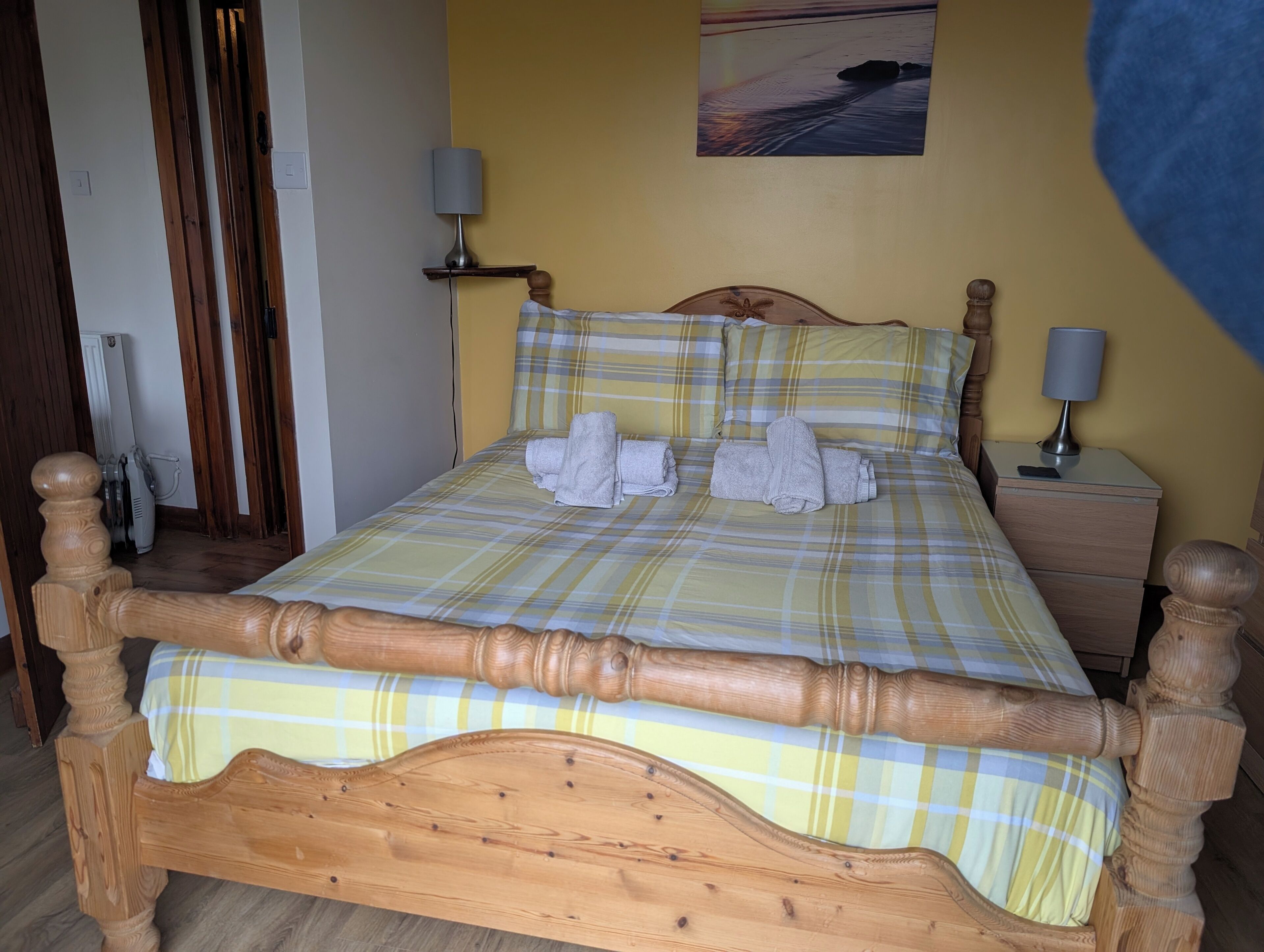 Una cama con colcha escocesa, cabecera de madera y dos lámparas de noche.