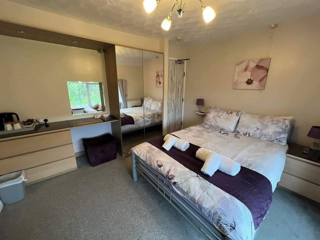A bedroom with a bed, a dresser, a mirror, and a window.