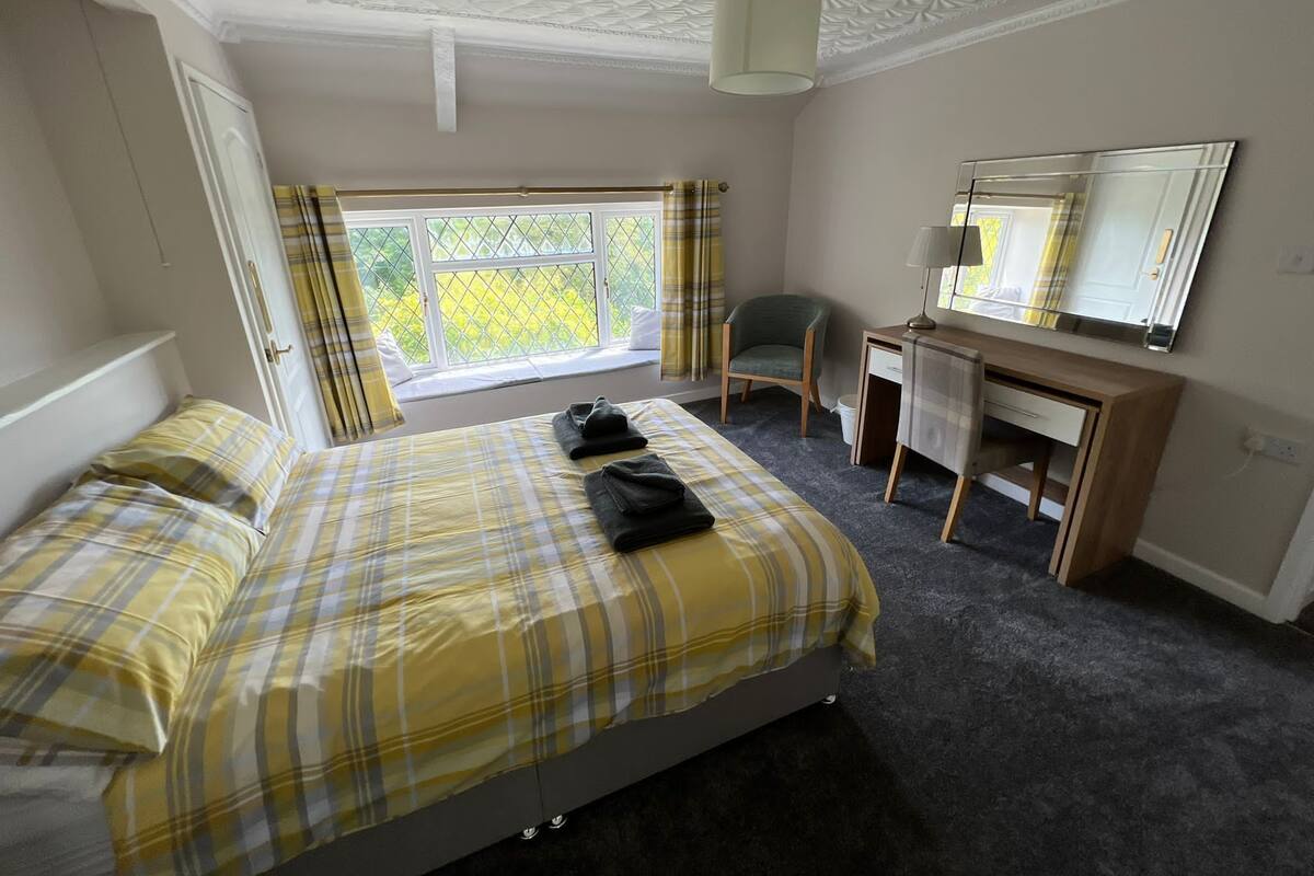 Une chambre à coucher avec un lit, un bureau, une chaise et une fenêtre avec des rideaux.