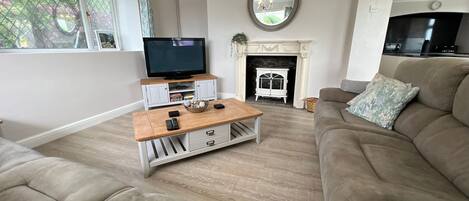 A living room with a beige sofa, a wooden coffee table, a television, and a fireplace.
