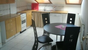A compact kitchen with a dining area, featuring a small table, chairs, and a dishwasher. - Gästehaus Willis (Goslar)