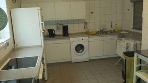A compact kitchen with a washing machine, a sink, and a refrigerator. - Gästehaus Willis (Goslar)