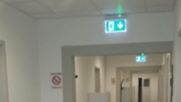 A hallway with a no-smoking sign, a trash bin, and a green exit sign. - Gästehaus Willis (Goslar)