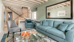 Un salon avec un canapé, des fauteuils et une table basse sur laquelle sont posées des boissons.
