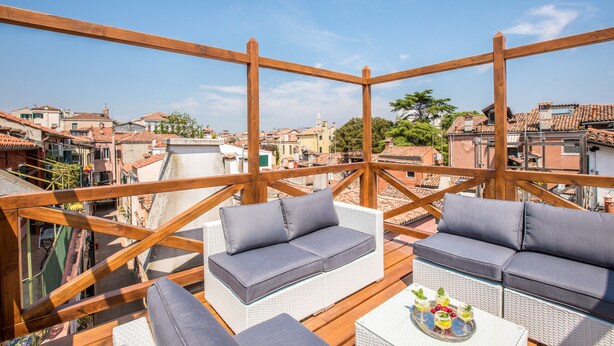 Une terrasse sur le toit, aménagée avec des meubles en osier et une table où sont disposées des boissons.