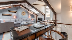 Un salon moderne avec un canapé, une table basse et un bureau avec un ordinateur portable. On y trouve également un téléviseur et un élément décoratif mural en forme de soleil rayonnant.