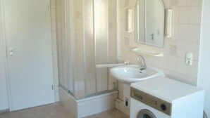 A bathroom with a shower, sink, and washing machine. - Gästehaus Harz (Goslar)