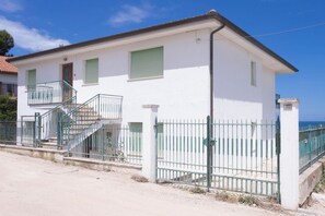 A two-story building with a balcony, a staircase, and a fenced area.