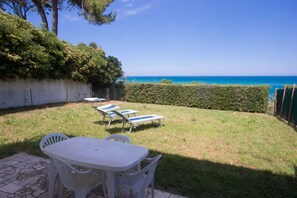 A patio with a table and chairs, lounge chairs, a hedge, and a view of the sea. - N129 - Numana, three-room apartment with sea view 200mt from the beach (Marcelli)