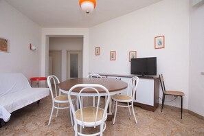 Una habitación con cama, una mesa de comedor con sillas, un televisor y un pequeño aparador.