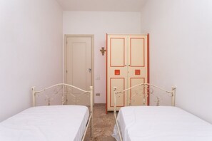 Una habitación con dos camas individuales, un armario y una puerta.