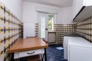 A compact kitchen with a wooden table, white cabinets, and patterned tiles.