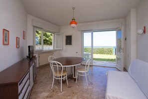 Una habitación con una mesa de comedor, sillas, un sofá, un televisor y vistas al exterior.