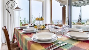 A dining table set with plates, glasses, and cutlery, overlooking a balcony with a view of the sea. - Villa Sun Total Relax (Alcamo)