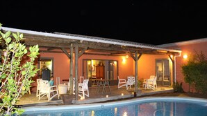 A poolside area with a covered patio, outdoor seating, and a pool. - Gite des Acacias (Carreau Accacia)